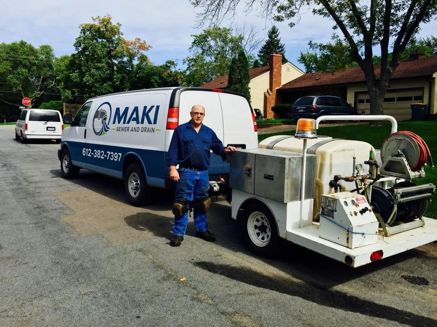 Rob Maki, owner of Maki Sewer and Drain, standing next to his service van and trailer-mounted hydro jetter on a Twin Cities residential street
